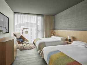 Guest room with two queen beds, an armchair, and a floor-to-ceiling window