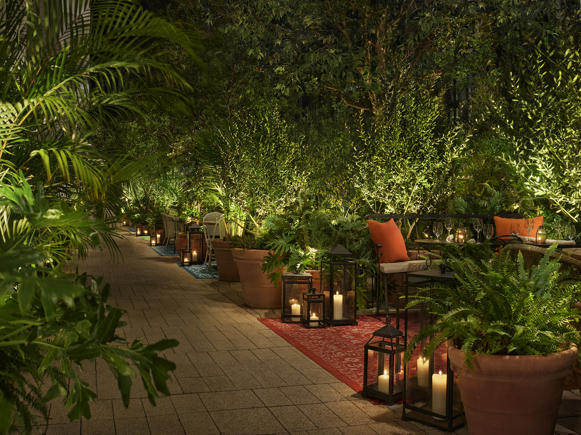Asientos semiprivados al aire libre con plantas tropicales y velas para ambientar