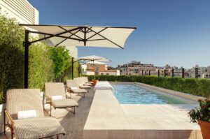 Sun loungers and umbrellas set next to a rooftop pool with views of Rome.  