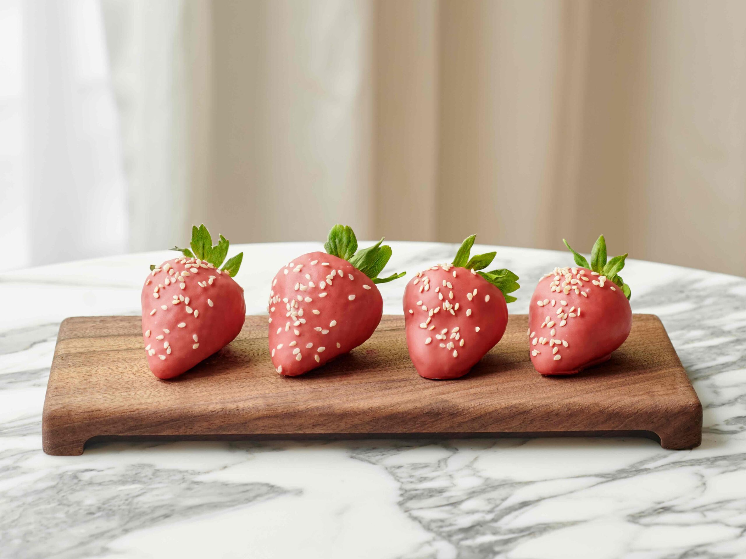 Chocolate covered strawberries on a wooden serving board.